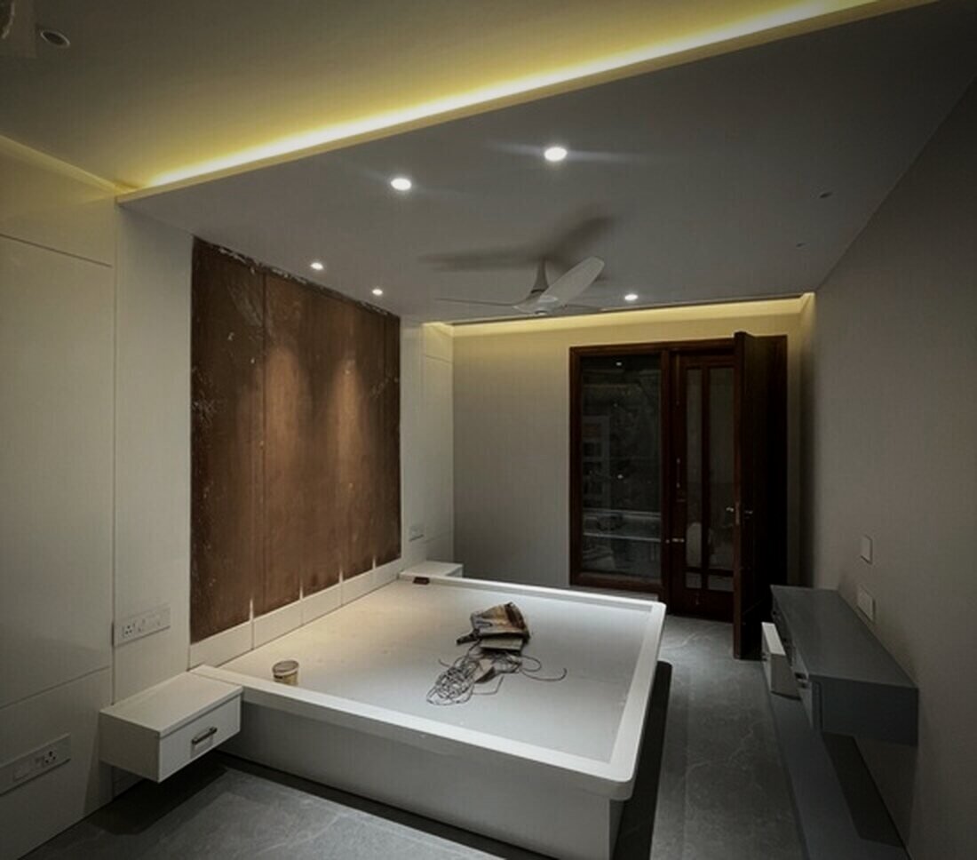 Bedroom with cove lighting and a timber feature wall